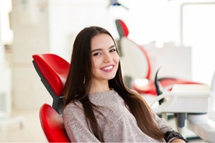 a patient smiling while sitting in the dentist’s chair