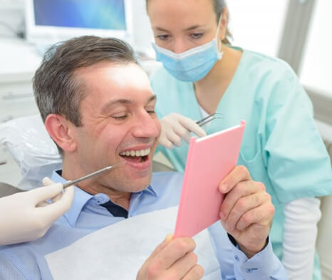 a patient checking his tooth after receiving a dental crown
