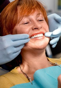 woman smiling while looking in dental mirror 