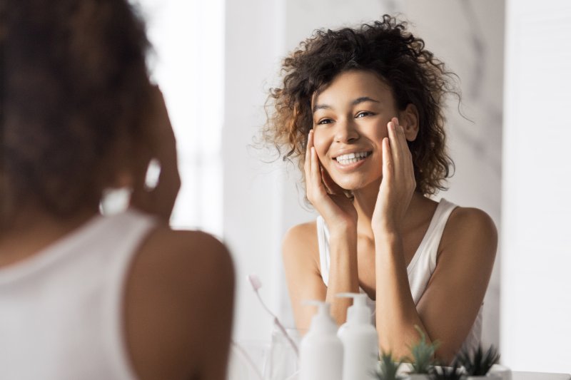 Patient smiling in the mirror, looking at their dental crowns