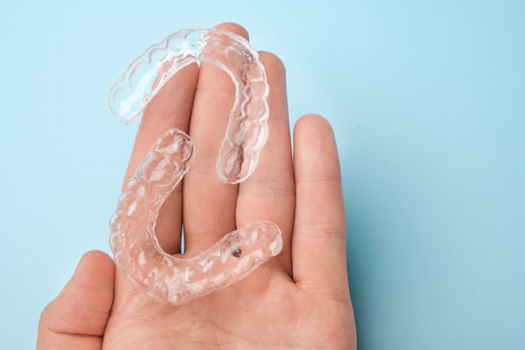 A hand holding a set of clear aligners.