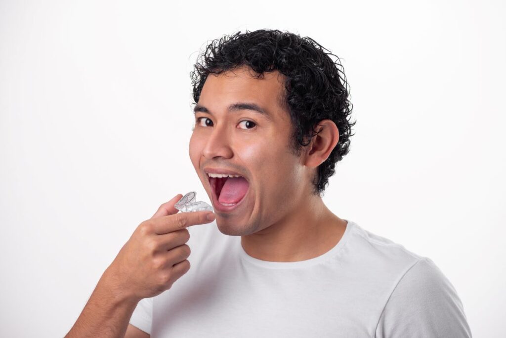 A man putting a Candid Pro Clear Aligner tray in his mouth.